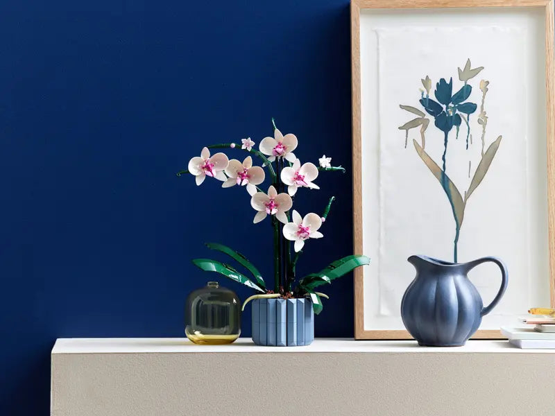 LEGO Icons Orchid Plant 10311 on a shelf with a painting and 2 vases